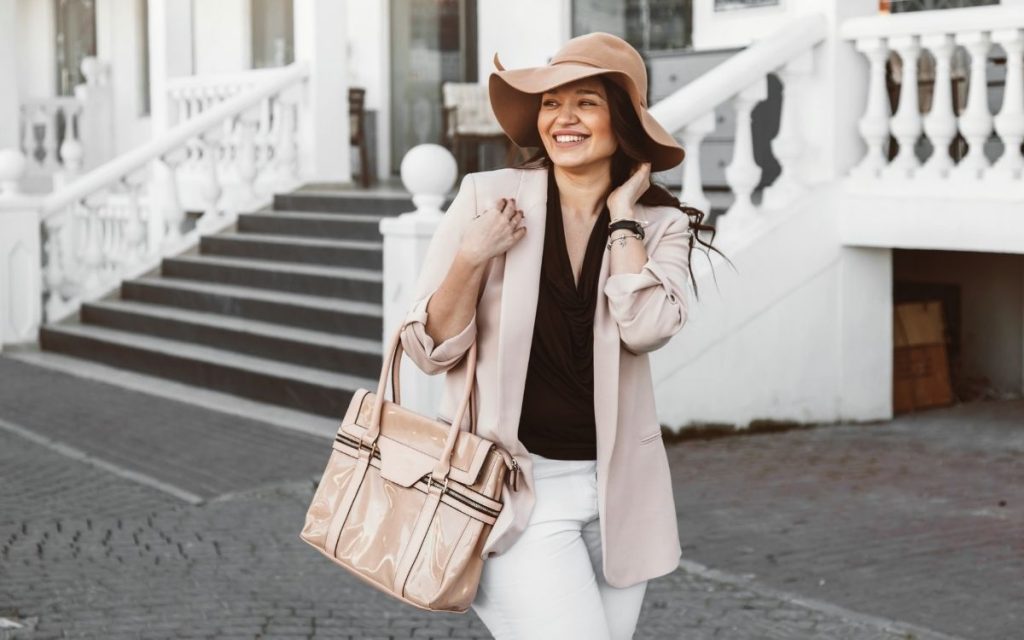 classic-style-woman-wearing-pink-blazer-with-hat-and-patent-satchel
