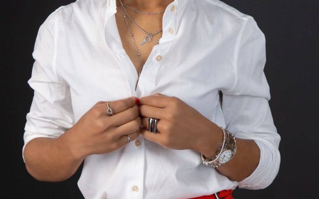 woman buttoning up a classic white button up shirt