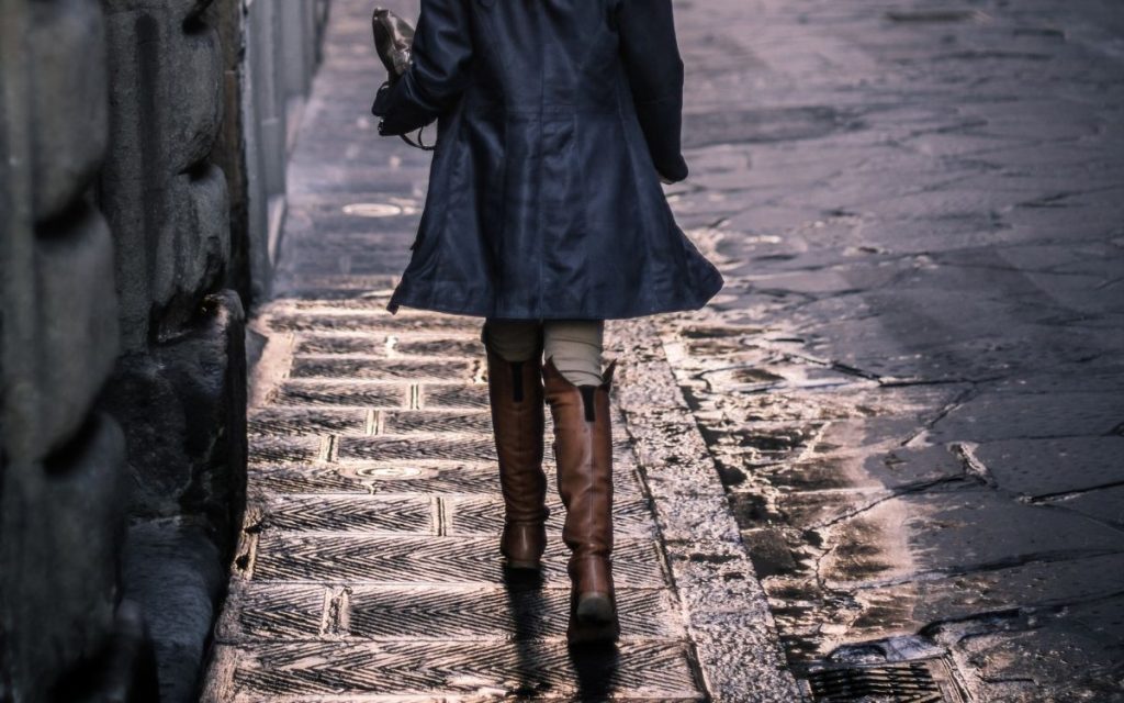 woman walking down street in classic tall leather riding boots