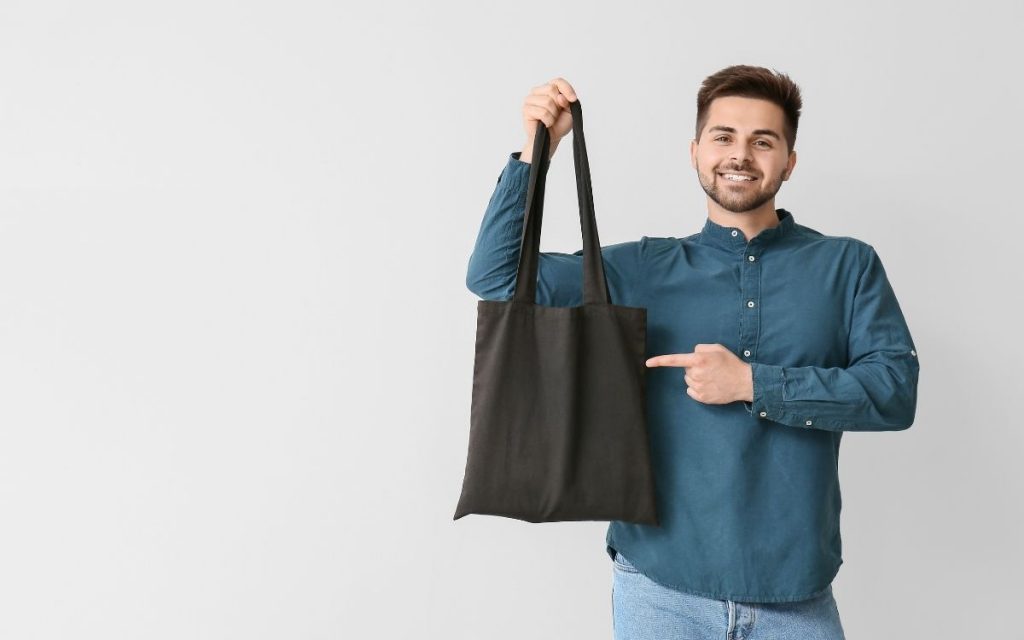 man holding tote bag to take to goodwill outlet the bins