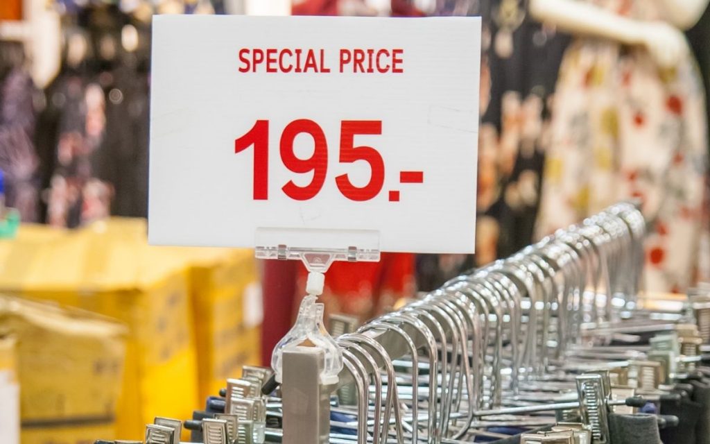 Sale price sign sits upon a cloths rack for sale.